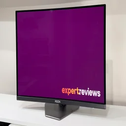 The AOC Agon Pro AG276QZD2 monitor on a white desk, pictured from an angle, showing the Expert Reviews logo on screen