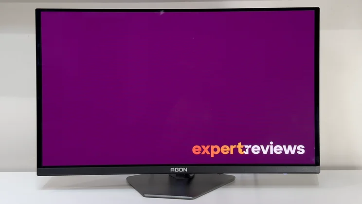The AOC Agon Pro AG276QZD2 monitor on a white desk, pictured from directly in front, showing the Expert Reviews logo on screen
