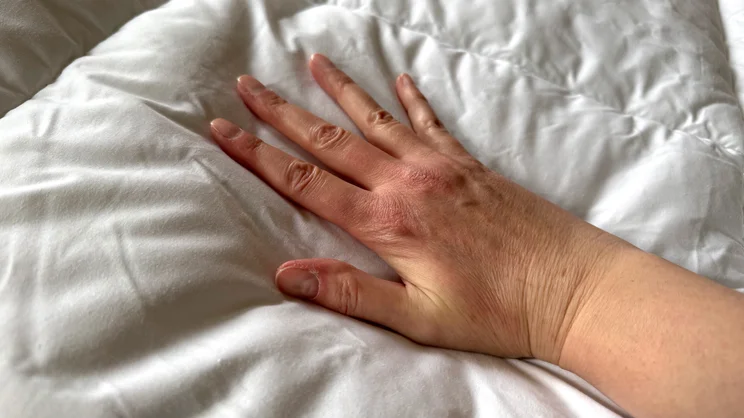 A hand pressing down on the surface of the Dorma Full Forever mattress topper