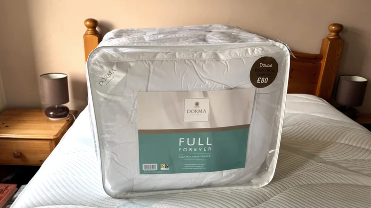 The Dorma Full Forever mattress topper in its bag, on top of a mattress