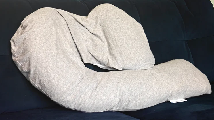 The Dreamgenii pregnancy pillow on a blue velvet sofa