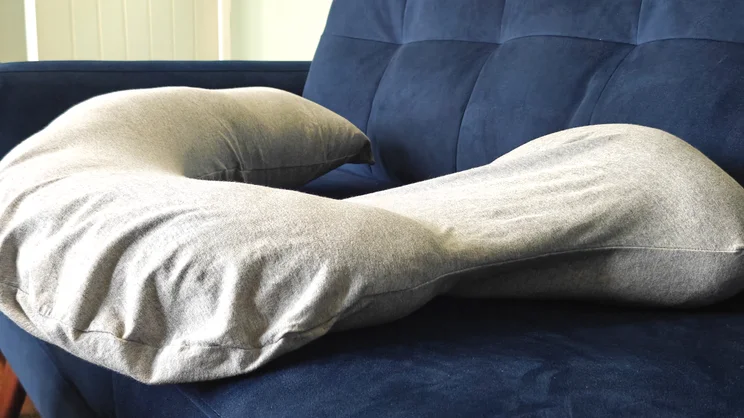 The Dreamgenii pregnancy pillow on a blue velvet sofa