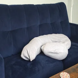 The Dreamgenii pregnancy pillow on a blue velvet sofa