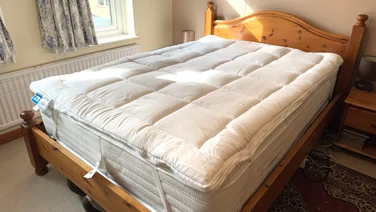 The Dreams Dream Team Ultimate Washable Mattress Topper on top of a mattress on a wooden bed frame