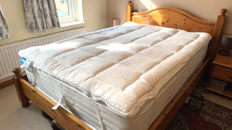 The Dreams Dream Team Ultimate Washable Mattress Topper on top of a mattress on a wooden bed frame