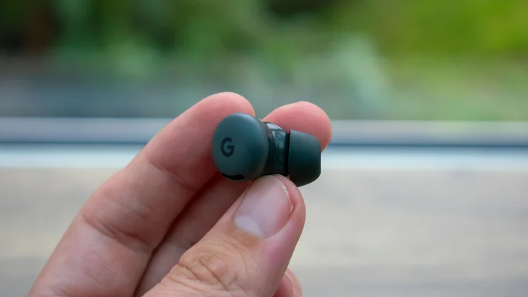Hand holding a Google earbud, showing the Google logo