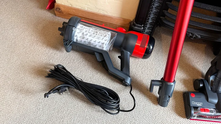 The main body and canister of the Henry Quick Corded vacuum cleaner on the floor. The vacuum's 10 metre long cable is wrapped up underneath it