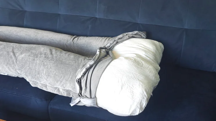The Nuliie Pregnancy Pillow on a blue sofa, with its outer cover partially removed