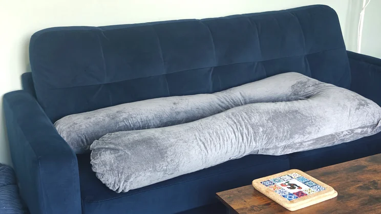 The Nuliie Pregnancy Pillow laid out flat on a blue sofa