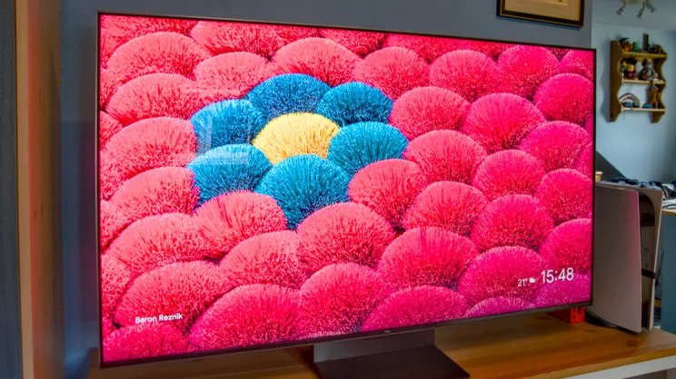 The TCL C7K TV on a cabinet showing a field of flowers on screen