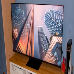 The TCL C7K TV on a cabinet next to a PS5