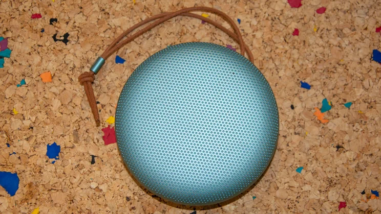 The Bang & Olufsen A1 3rd Gen Bluetooth speaker on a cork table with its leather strap positioned above it