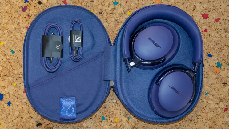 The Bose QuietComfort Ultra Headphones (2nd Gen) inside their open carrying case on a cork table