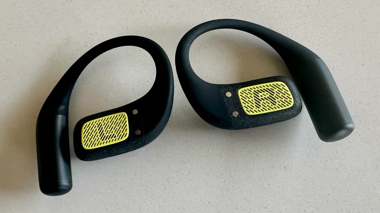 The JBL Endurance Zone open-ear headphones lying face up on a white table showing the Left and Right markings on the inside of the earpieces