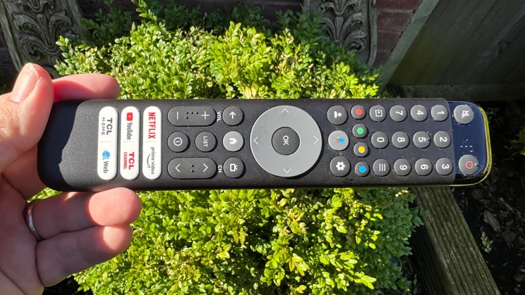 The remote control included with the TCL P7K QLED TV being held in a man's hand