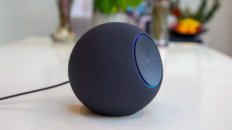 The Amazon Echo Studio 2025 pictured from the left, on a white dining table with flowers in the background