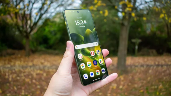 Motorola Edge 70 in hand, in front of trees