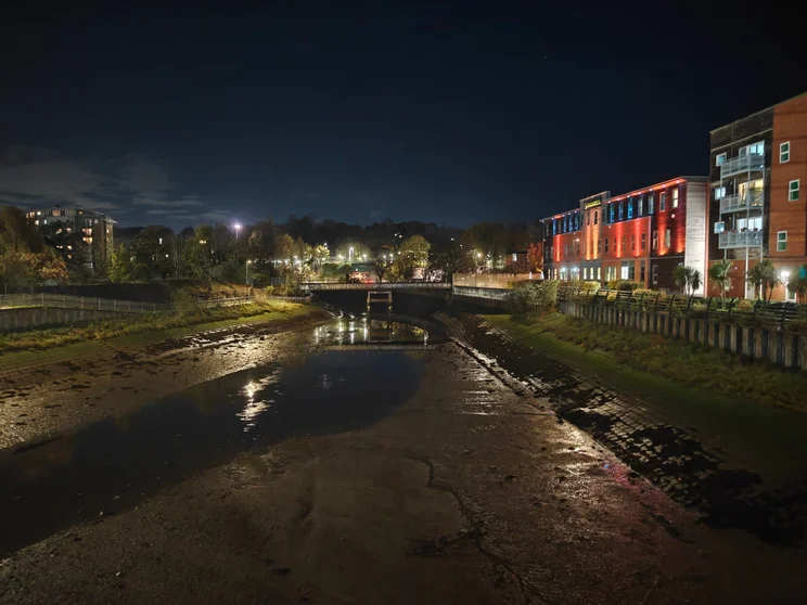 Night shot of a river at low tide with buildings on both sides
