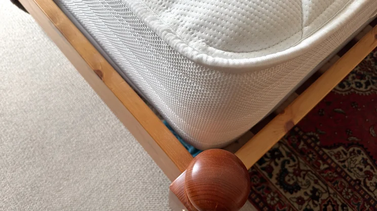 The corner of the Slumberland Air 6.0 Memory mattress, on a wooden bedframe