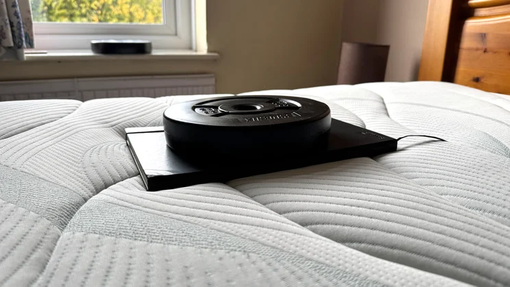 Testing sinkage of the Slumberland Air 6.0 Memory mattress, using a notebook and a weight