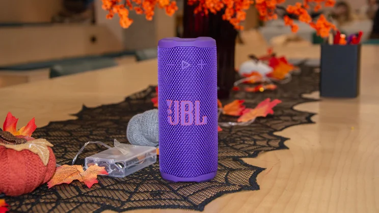 The JBL Grip portable Bluetooth speaker on a table covered in Halloween decorations