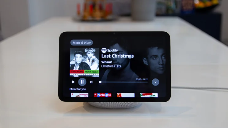 The Amazon Echo Show 8 (4th gen, 2025) pictured from the front on a white table, showing music controls