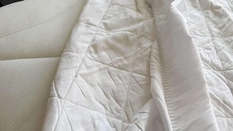 A closeup of the Dusk Luxury Quilted Mattress Protector, half pulled away from a mattress