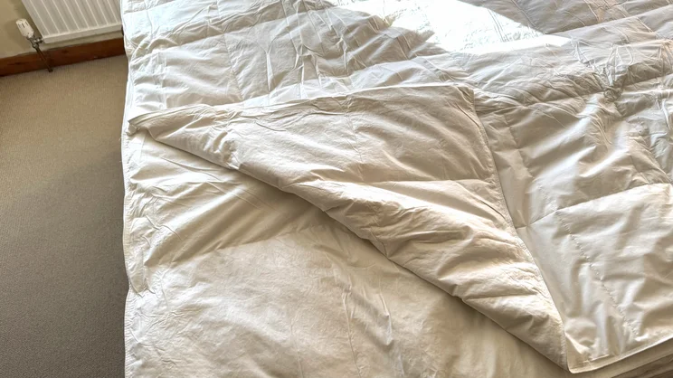 A corner of one of the Dusk Supreme Goose Down mattress topper's layers folded over