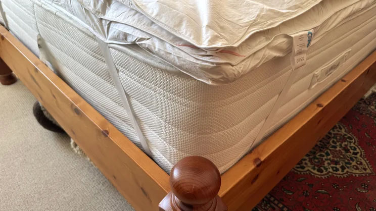 A corner of the Dusk Supreme Goose Down mattress topper attached to a mattress