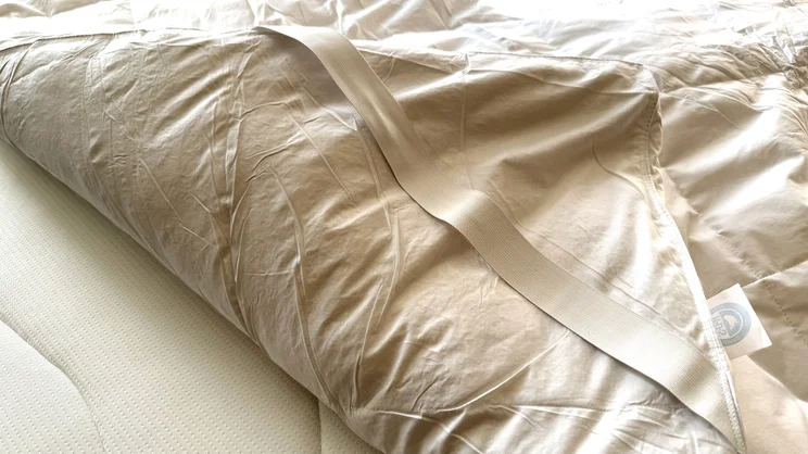 A corner of the Dusk Supreme Goose Down mattress topper with corner strap