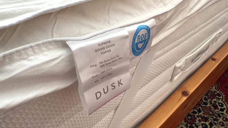 A closeup of the Dusk Supreme Goose Down mattress topper's care label