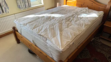 The Dusk Supreme Goose Down mattress topper on a mattress in a bedroom