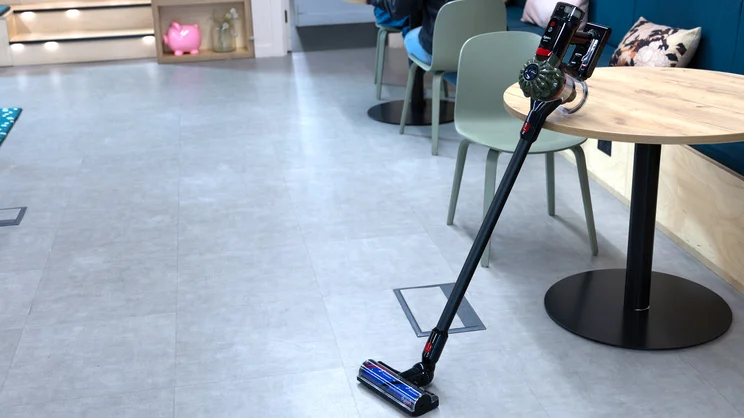 The Dyson V8 Cyclone vacuum cleaner leaning on a table in an office