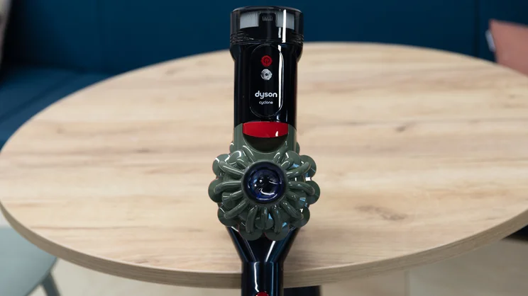 The handle of the Dyson V8 Cyclone vacuum cleaner, leaning on a table in an office