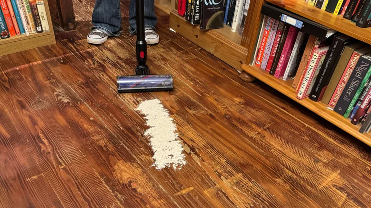 The Dyson V8 Cyclone vacuum cleaner being used on a hard wood floor to clean flour