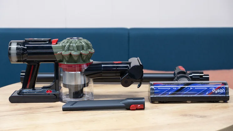 The Dyson V8 Cyclone vacuum cleaner handle on a table, alongside office attachments