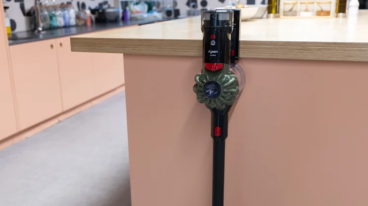 The Dyson V8 Cyclone vacuum cleaner leaning against a kitchen island in an office