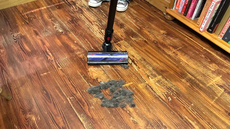 The Dyson V8 Cyclone vacuum cleaner being used on a hard wood floor to clean pet hair