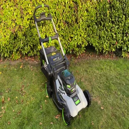 The Ego LM2236E-SP lawn mower on a lawn, in front of a hedge