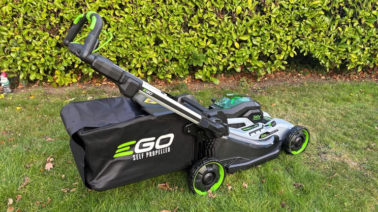 The LM2236E-SP lawn mower, with its grass collection bag attached, on a lawn in front of a hedge