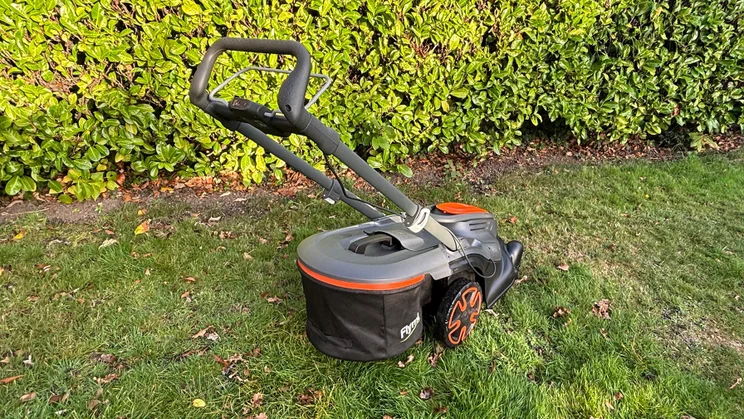 A rear view of the Flymo 36V Ultramow 460 Duo, on a lawn in front of a hedge