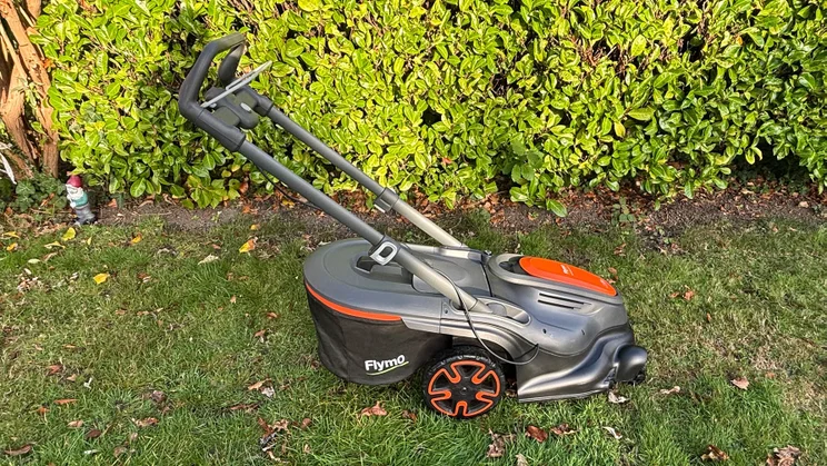 A side view of the Flymo 36V Ultramow 460 Duo, on a lawn in front of a hedge
