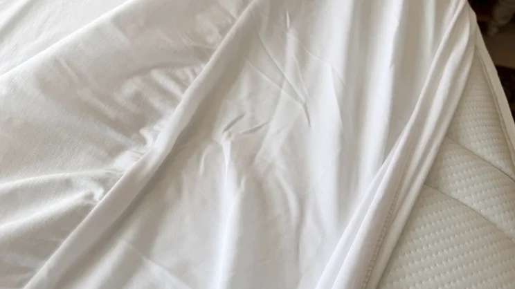 A closeup of the surface of the Nectar mattress protector, partially covering a mattress