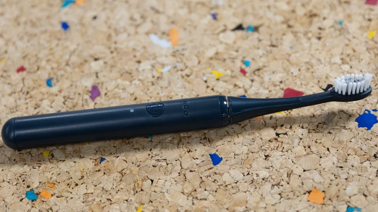 The Ordo Sonic Edge toothbrush laid down on a multicoloured cork table
