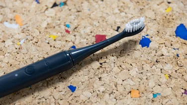 The Ordo Sonic Edge toothbrush laid down on a multicoloured cork table
