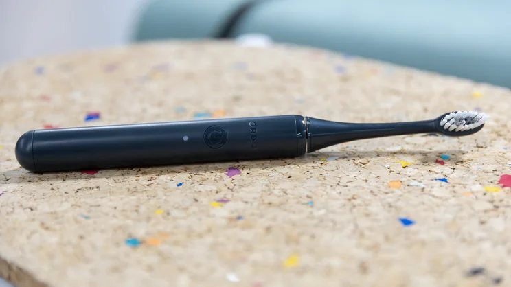 The Ordo Sonic Edge toothbrush laid down on a multicoloured cork table