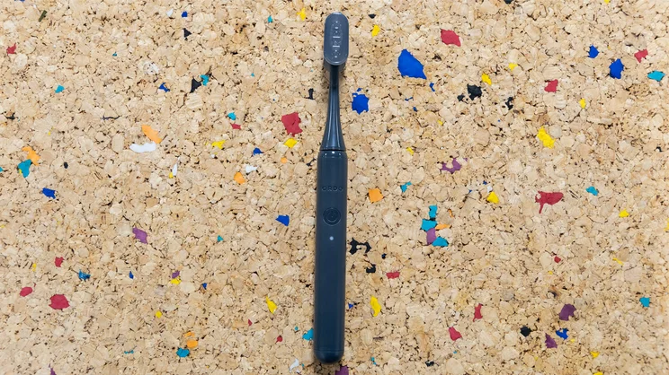 A bird's eye view of the Ordo Sonic Edge toothbrush, laid down on a multicoloured cork table