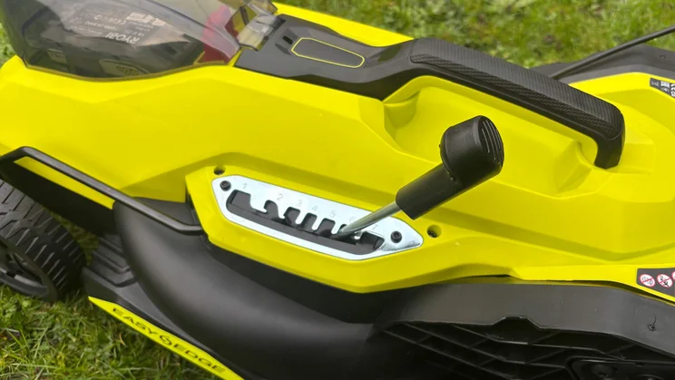 A closeup of the Ryobi RY18LMX33A lawn mower's height adjuster