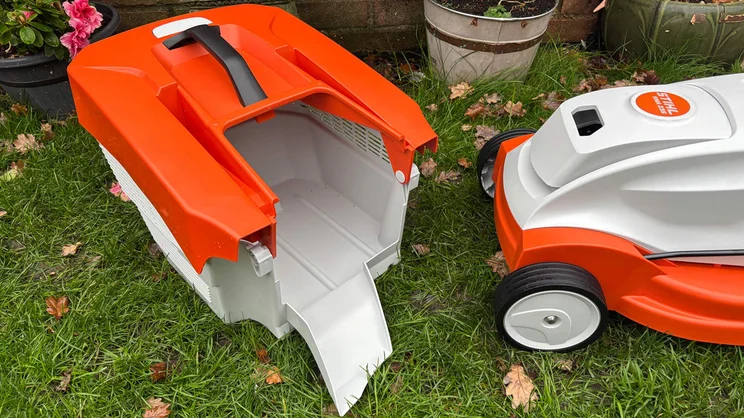 The Stihl RMA 235 lawn mower with grass collector removed and placed in front of it