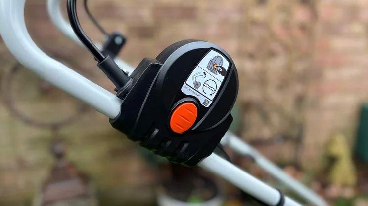 A closeup of the Stihl RMA 235 lawn mower's lock switch on its handle